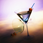Vodka Martini with Olives; Tipped Martini Glass in Background