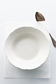 An empty plate on a piece of paper with a spoon next to it
