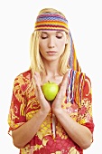 A young woman with a headband holding a green apple
