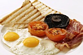 English breakfast with fried egg, bacon, tomatoes, mushrooms and toast