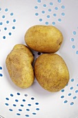 Drei Kartoffeln liegen in einem Sieb