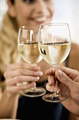 Young woman clinking white wine glass