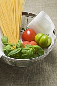 Tomatoes, spaghetti and basil in a sieve