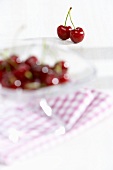 A pair of cherries and cherries in a glass bowl