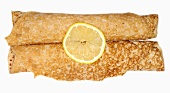 Two rolled-up pancakes with sugar and lemon