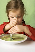 Girl cutting a broccoli floret in vegetable soup