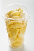 Pineapple chunks in a plastic cup with a lid