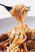 Spaghetti on a fork with meatballs and tomato sauce