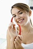 Young woman holding two red chillies in her hands