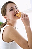 Young woman biting into a croissant