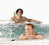 Young couple with sparkling wine in whirlpool