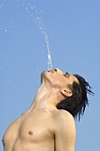 Mann spritzt mit Wasser aus dem Mund