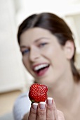 Woman holding a strawberry with her fingertips