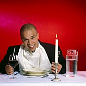 Mann sitzt vor leerem Teller mit Wasser und Wein