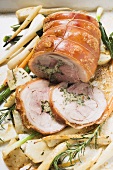 Rolled pork roast with herb stuffing on root vegetables