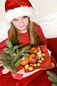 Girl holding plate of nuts and apples in her hands