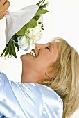 Smiling woman smelling bouquet of white roses