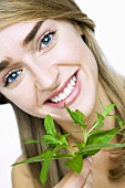 Young woman holding fresh basil in her hand