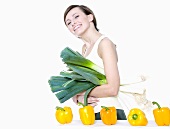 Young woman with leeks and peppers