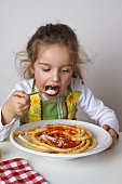 Small girl eating macaroni with tomato sauce and Parmesan