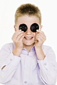 Boy holding two liquorice wheels in front of his eyes