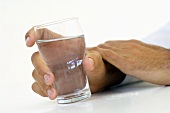 Hand hält ein Glas Wasser