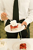 Man holding plate with piece of strawberry flan and cream