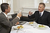 Two men drinking glasses of water during a business meal