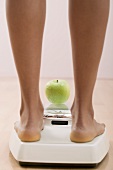 Young woman on bathroom scales with apple