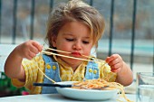 Girl eating spaghetti with tomato sauce