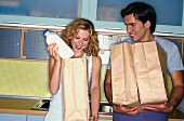 Couple in kitchen with paper bags of shopping