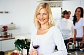 Blonde woman in kitchen with glass of red wine