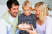 Father, mother and son celebrating birthday with cake