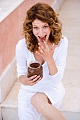 Woman sneaking a fingerfull from a jar of chocolate spread