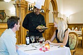 Couple eating dinner in restaurant being served by chef