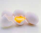 A cracked-open egg between intact eggs