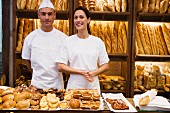 Two shop assistants in bakery with pastries and baguettes