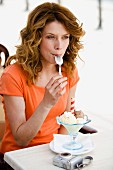 Woman eating ice-cream and licking spoon