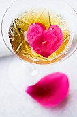 Heart-shaped petal in glass of sparkling wine