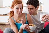 Couple eating biscuits in living room