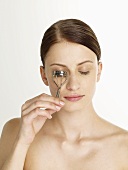 Woman with an eyelash curler