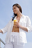 Woman with a drink standing by swimming pool