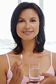 Frau mit Tablette und Wasserglas
