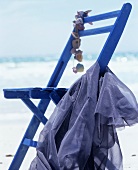 Wooden chair decorated with shells and blue fabric by sea