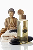 Massageöl und Warmsteine, Buddhafigur im Hintergrund