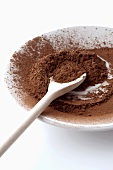 Cocoa powder on plate with wooden spoon