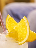 Drink with orange slices on glass rim, person in background