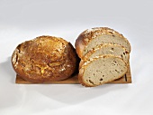 Loaves of bread, whole & partly sliced, on a wooden board