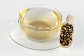 Tasse Tee mit getrockneter Nussgraswurzel auf einer Schaufel