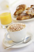 A cup of cappuccino, orange juice and brioches